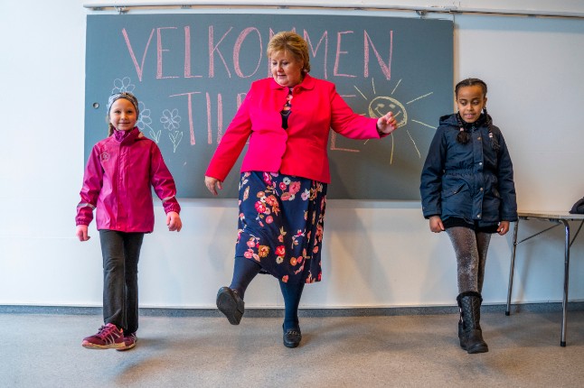 Nórska premiérka Erna Solberg ukazuje, ako možno niekoho pozdraviť s dodržaním odstupu. / Foto: Håkon Mosvold Larsen / NTB
